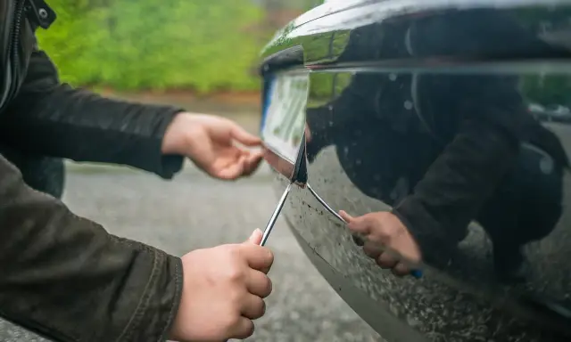 Ręce przykręcają tablicę rejestracyjną do zderzaka. Ubezpieczenie OC niezarejestrowanego auta jest kluczowe przed jazdą.