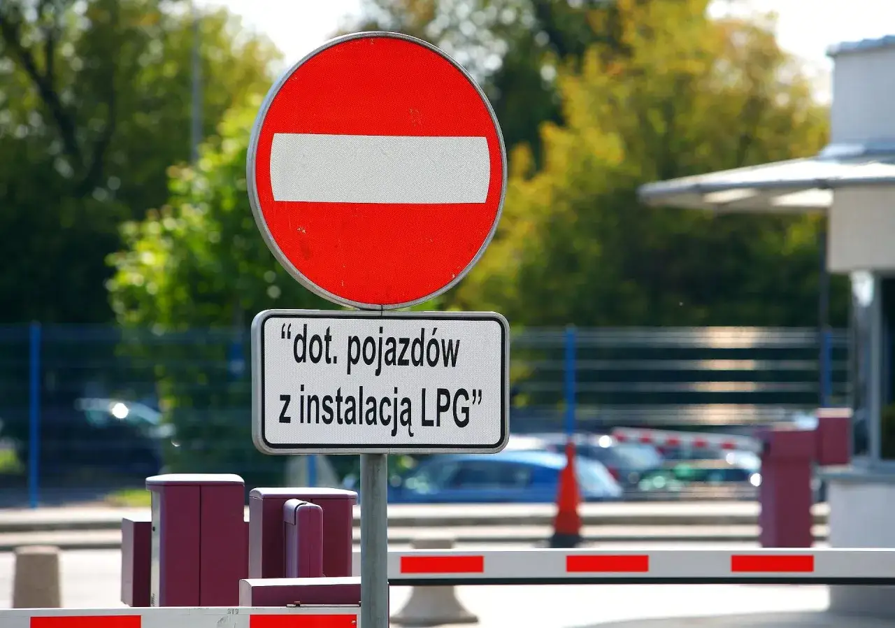 Znak zakaz wjazdu dla pojazd&oacute;w z instalacją LPG. Brama wjazdowa zamyka przejazd.