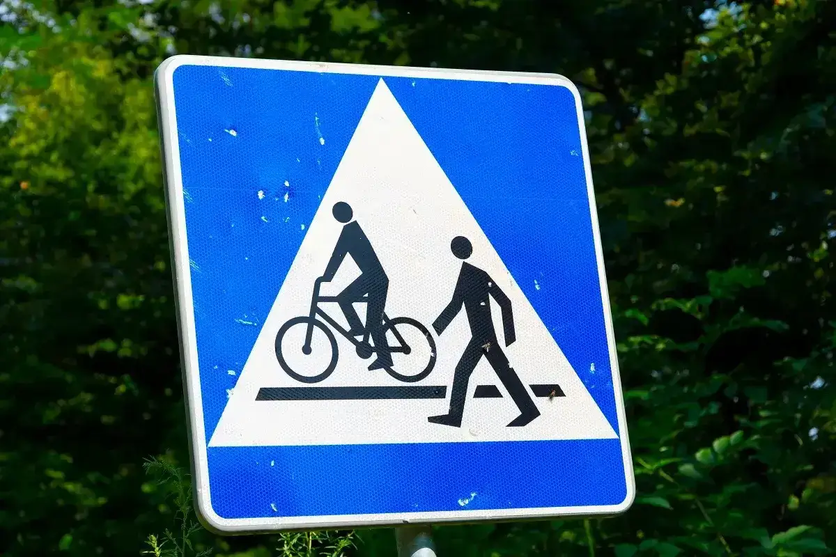 Znak ostrzegawczy: rowerzysta na przejeździe rowerowym i pieszy. Uważaj na drodze!