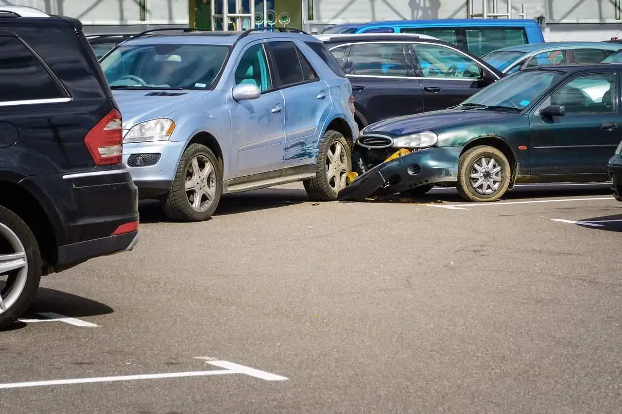 Uszkodzone samochody na parkingu po kolizji. Czy to wypadek, który kwalifikuje się do OC?