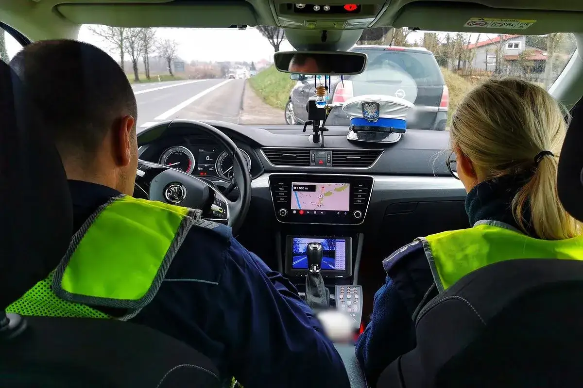 Policjanci w radiowozie patrolują drogę, gotowi do interwencji w przypadku wykrycia jazdy bez prawa jazdy.