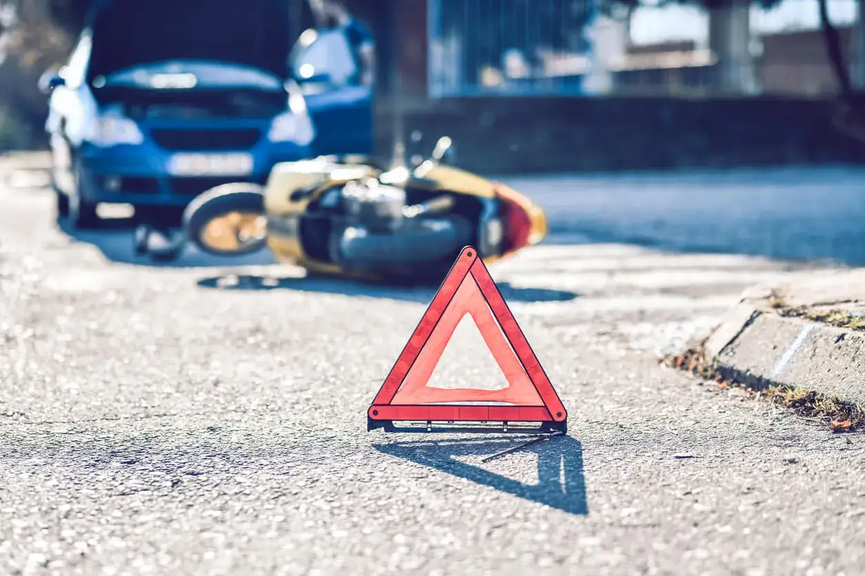 Wypadek drogowy: przewr&oacute;cony motocykl i samoch&oacute;d z otwartą maską. Tr&oacute;jkąt ostrzegawczy na drodze. Czy nieopłacona polisa OC jest ważna w takiej sytuacji?