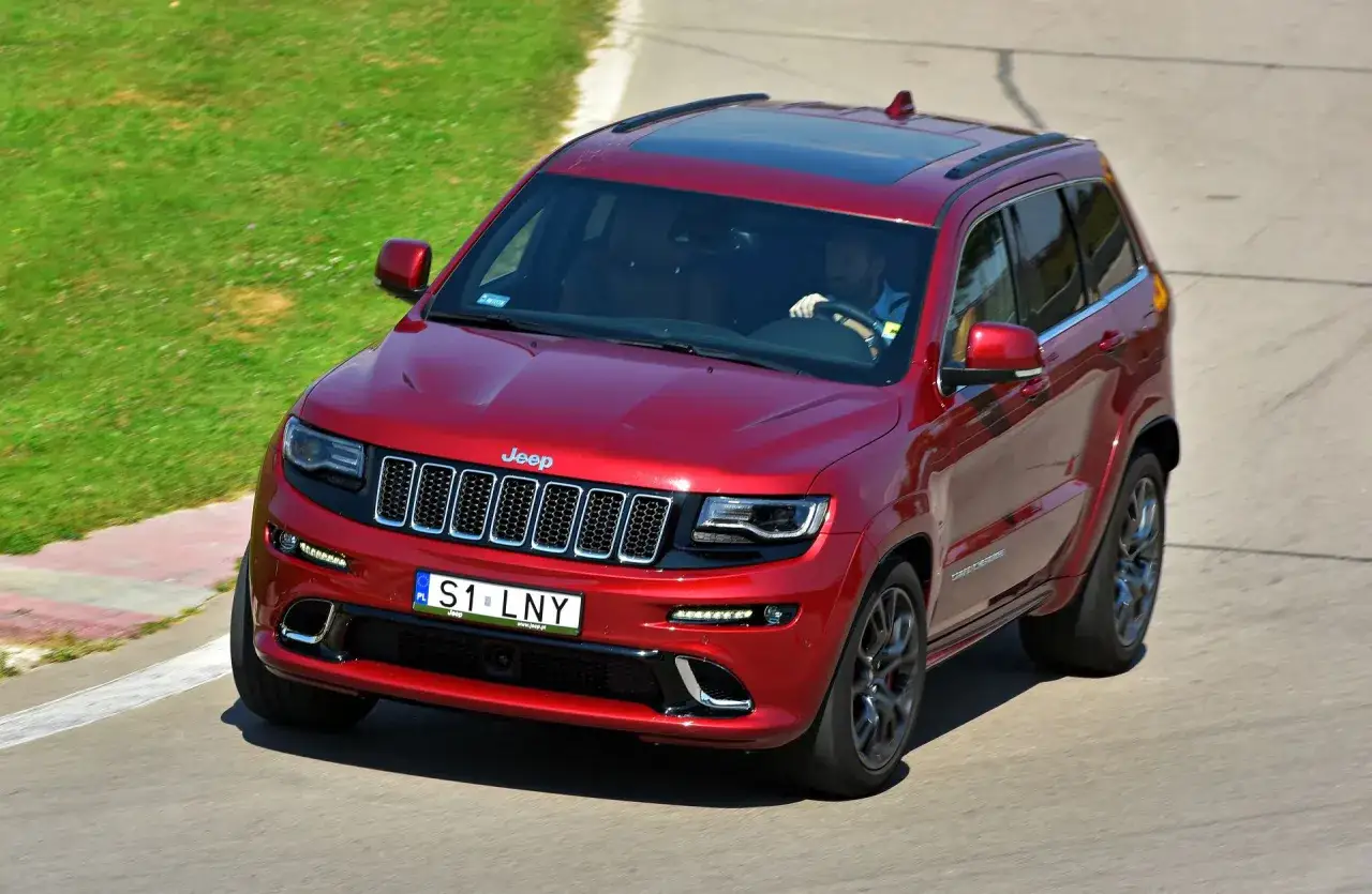 Czerwony Jeep Grand Cherokee na torze wyścigowym, z indywidualną tablicą rejestracyjną 