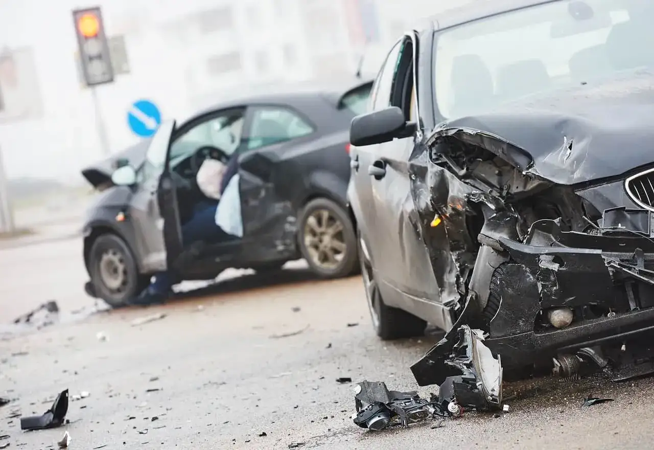 Dwa rozbite samochody na drodze. Wypadek drogowy, który może wpłynąć na sumę gwarancyjną OC.
