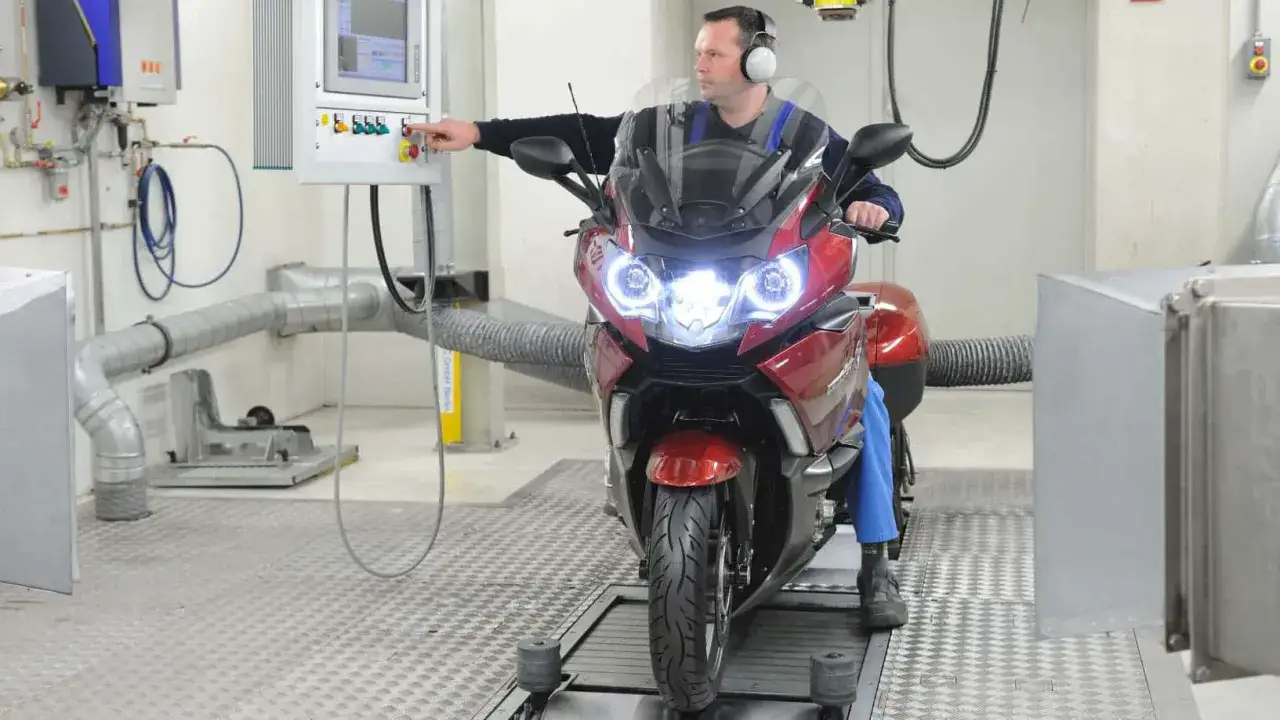 Mechanik w słuchawkach przeprowadza przegląd motocykla po terminie na hamowni.